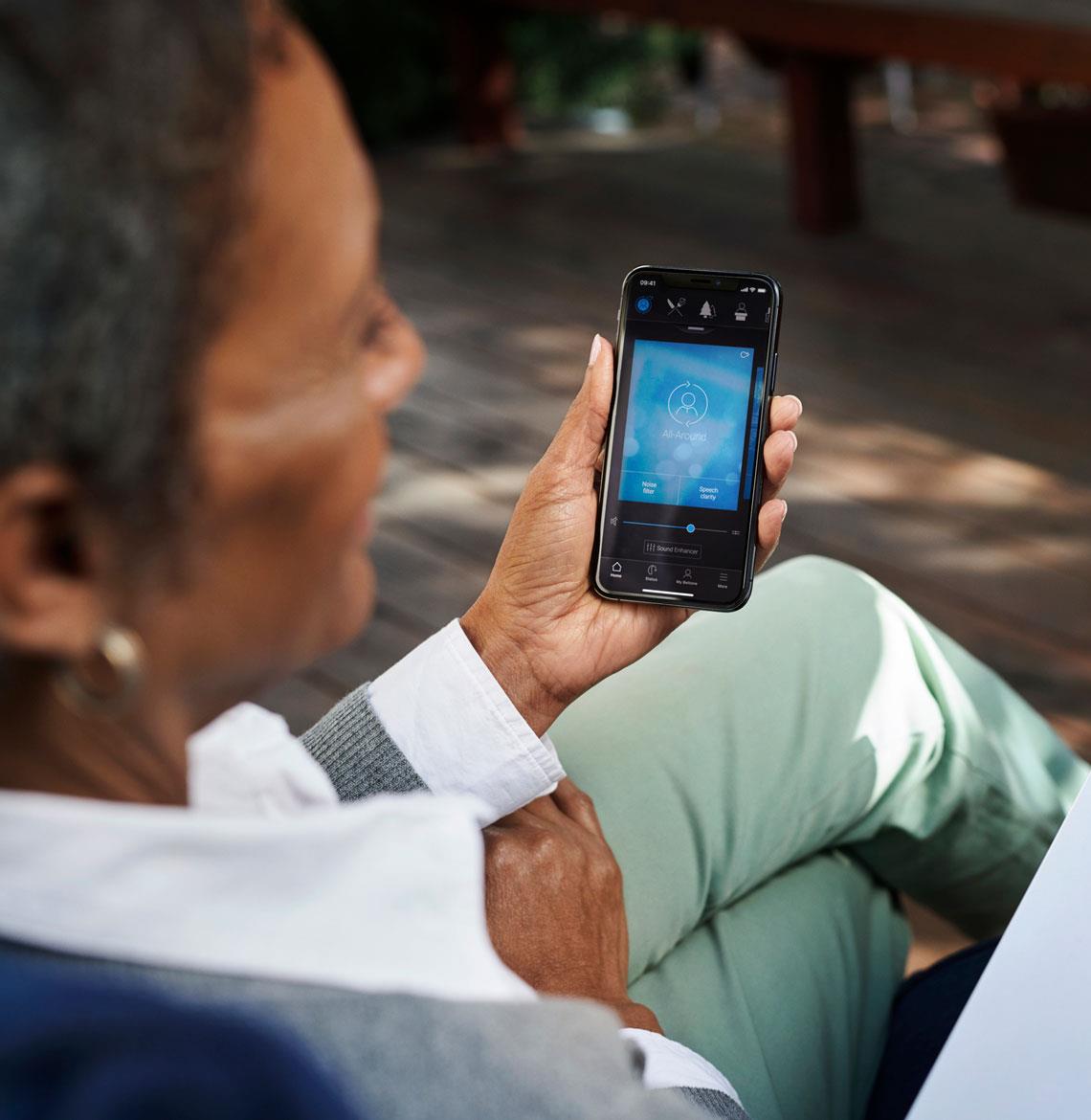 woman using hearing aid app to request remote assistance services - Beltone HearMax app