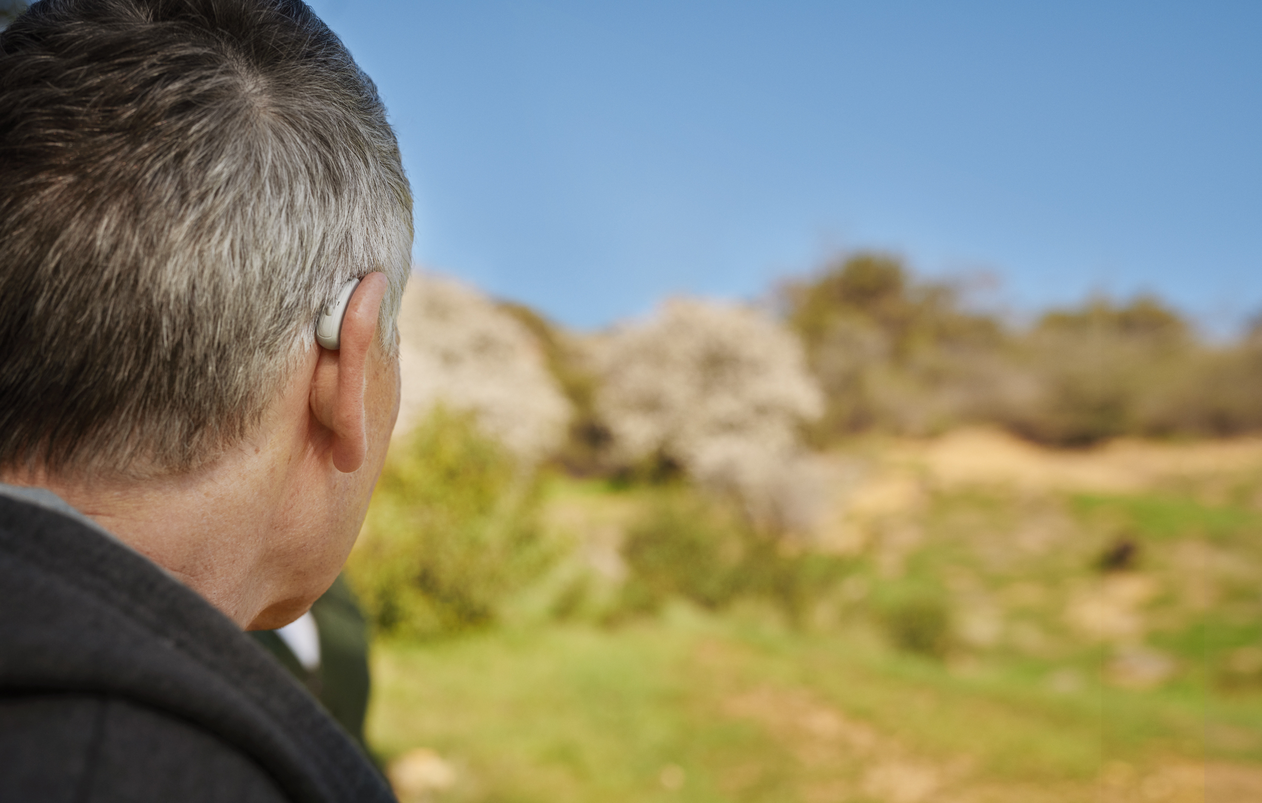 Mand, der har Beltone Legend høreapparater på og smiler og taler til en kvinde. 
